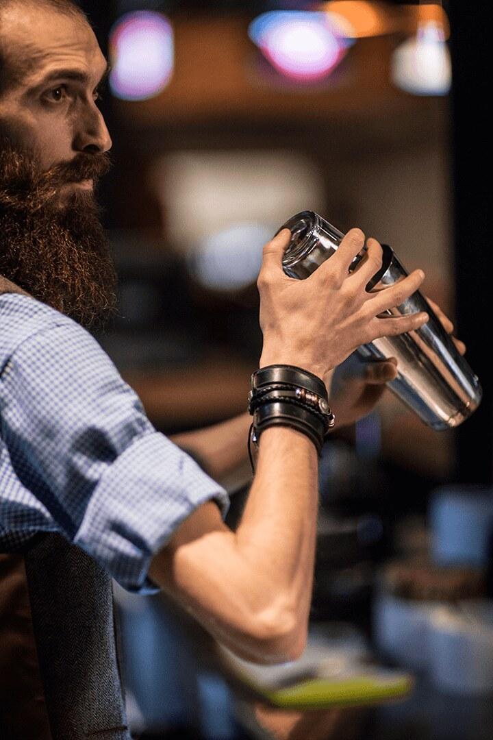 A bartender working a shaker behind the bar