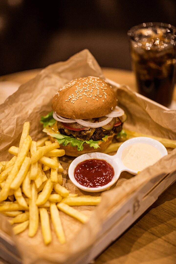 A burger with fries and a cold drink